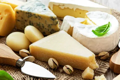 Un assortiment de fromages, dont du bleu et du brie, avec des pistaches. Le fromage est-il une protéine ? Oui, c'est une excellente source.