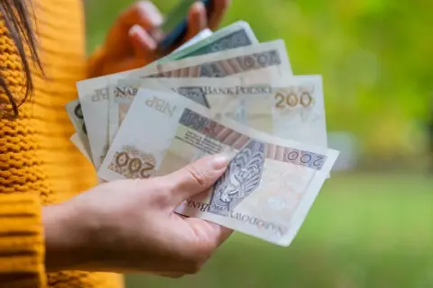 Dłoń trzyma polskie banknoty 200 zł. To może być dodatek wyrównawczy, który pomoże w codziennych wydatkach.