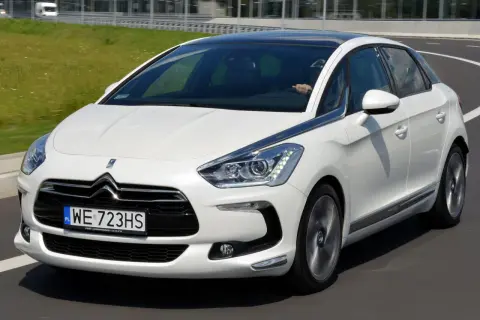 Biały Citroen DS5 na drodze. Kierowca za kierownicą. Wiele osób szuka pozytywnych **citroen ds5 opinie** przed zakupem.