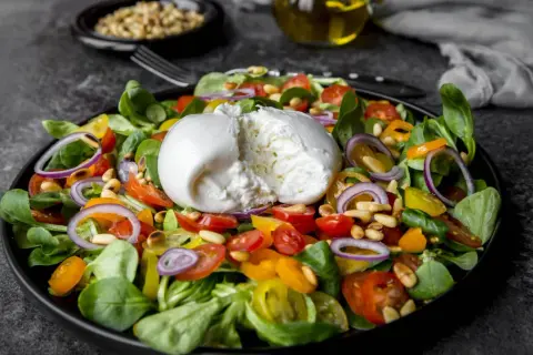 Frischer Salat mit cremiger Burrata, Tomaten, Zwiebeln und Pinienkernen. Perfekt für eine leichte Mahlzeit, auch in der Schwangerschaft.