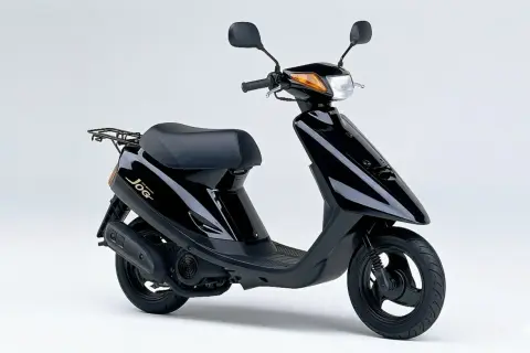 Ciclomotor negro Yamaha Jog, un clásico de los ciclomotores de los 90, con asiento y parrilla trasera.