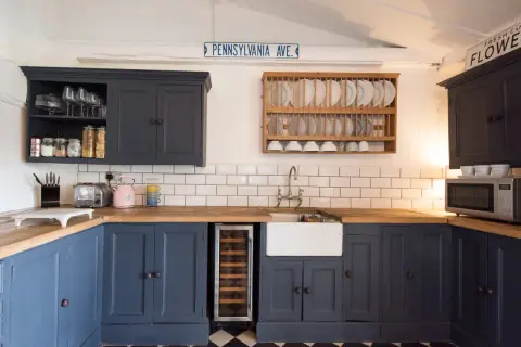 Cocina reformada sin obras: armarios azul marino, encimera de madera, fregadero blanco y suelo de baldosas a cuadros.