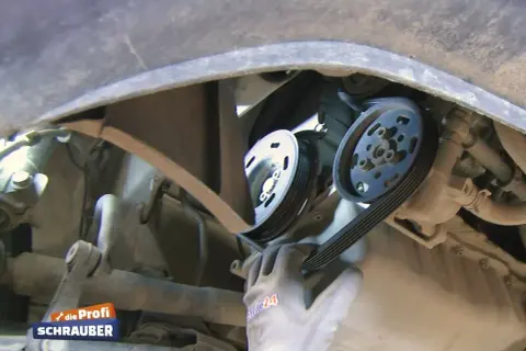 Ein Mechaniker wechselt einen Keilriemen. Die Keilriemen wechseln Kosten sind oft überschaubar.