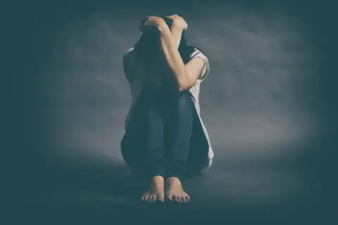 Osoba skulona, z rękami na głowie, symbolizuje walkę z depresją lekooporną.