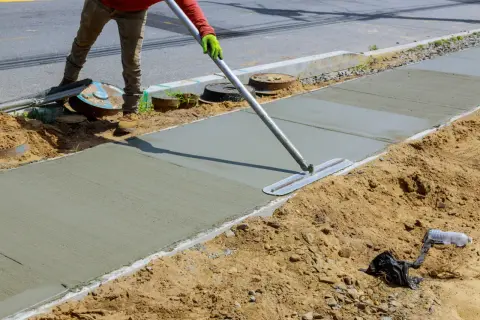 Robotnik wygładza świeży beton B25. Sprawdź aktualną beton b25 cena za m3, by zaplanować budowę chodnika.