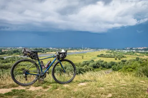 Rower gravelowy z sakwami na tle burzowego nieba nad Wisłą. Przygotowany na wyprawę Wisła 1200.