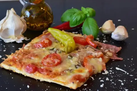 Pyszny kawałek pizzy z pomidorami i papryką, czosnkiem i bazylią. Zastanawiasz się, ile może leżeć pizza w lodówce?