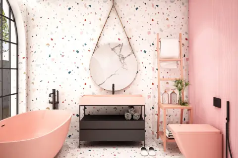 Bagno moderno con vasca rosa, lavabo, specchio rotondo e un vivace **pavimento in graniglia di marmo** multicolore.