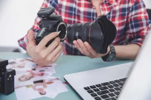 Fotograf przygotowuje sprzęt. Zastanawia się, czy robienie zdjęć z ukrycia jest karalne, przeglądając wydrukowane fotografie.