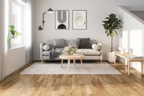 Ljust golv inspiration i ett modernt vardagsrum med grå soffa, rund soffbord och en stor grön växt.