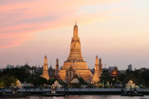Zachód słońca nad rzeką w Bangkoku, stolicy Tajlandii pełna nazwa. Wspaniała świątynia Wat Arun rozświetlona złotym blaskiem.