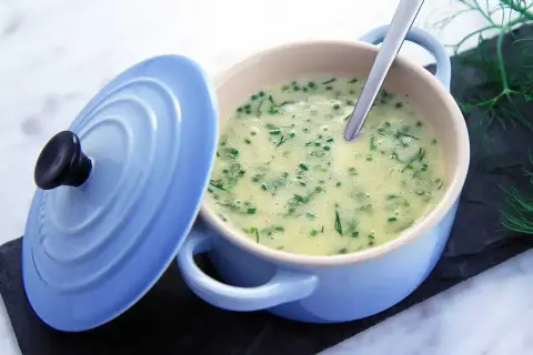 Krämig soppa med dill och gräslök, serverad i en ljusblå gryta. En sked vilar i den lena beurre blanc-såsen.