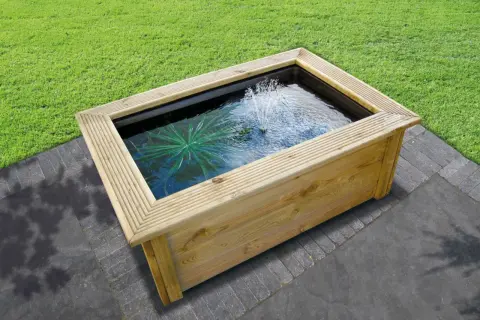 Un bassin préformé hors sol en bois avec une fontaine et une plante aquatique, prêt à être installé dans un jardin.