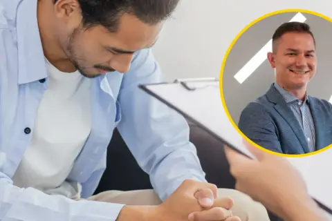 Mężczyzna w niebieskiej koszuli pochyla się nad dokumentami, obok uśmiechnięty urolog. Tak wygląda badanie prostaty u urologa.