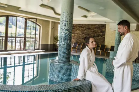 Para relaksu w Hotel Elbrus Spa & Wellness. Para w szlafrokach przy basenie, z widokiem na góry.
