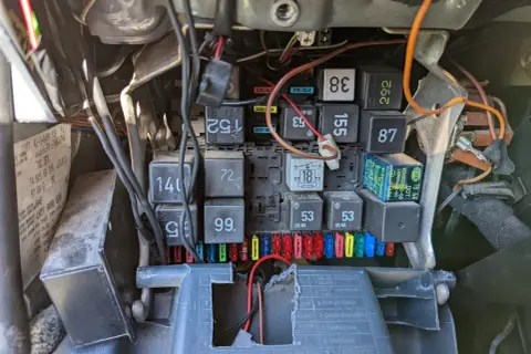 Widok na skrzynkę bezpieczników i przekaźników w samochodzie. Widać bezpiecznik od kierunkowskazu, oznaczenie 18, oraz inne elementy instalacji elektrycznej.