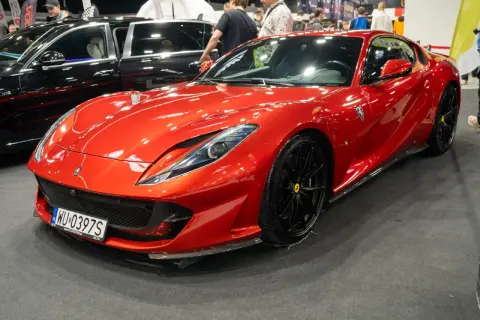 Błyszczący, czerwony Ferrari 812 Superfast z czarnymi felgami na wystawie motoryzacyjnej.