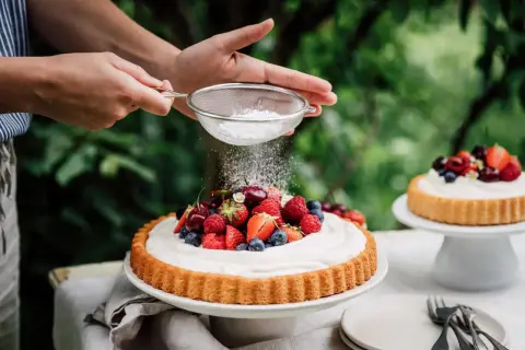 Ein sommerlicher Kuchen mit frischen Beeren wird mit Puderzucker bestäubt.