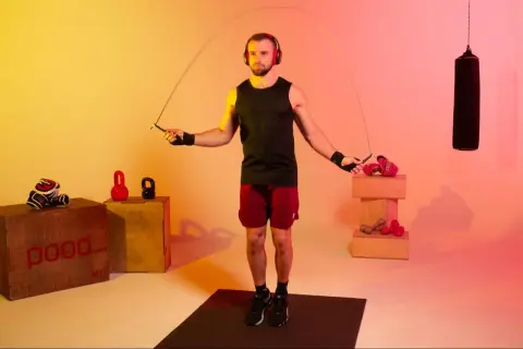 A boxer with headphones jumps rope, a common training method to improve stamina and agility. How long do boxers jump rope? It varies, but often for 10-15 minutes per round.