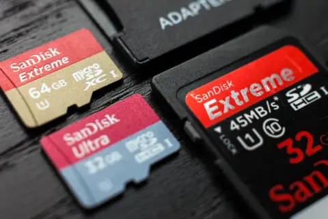 Karty pamięci SanDisk Extreme i Ultra, w tym 64GB microSDXC i 32GB microSDHC, obok adaptera. Różnice między SDXC a SDHC są widoczne.