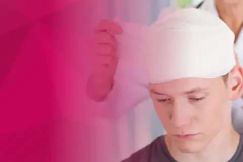 Młody mężczyzna przechodzi bandażowanie głowy przez lekarza.