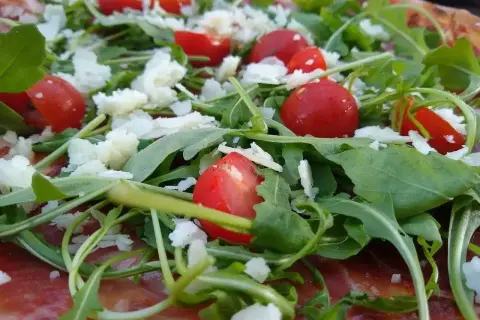 Pizza z rukolą, pomidorkami i parmezanem. Rukola właściwości zdrowotne dodają jej lekkości i świeżości.