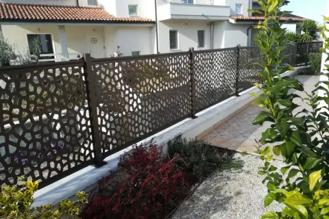 Modern metal fence with geometric cutouts, offering privacy and style. Perfect for **ideas ocultación jardin** and creating a chic outdoor space.