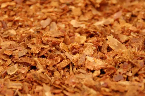 Zbliżenie na drobno pokruszony, brązowy propolis.