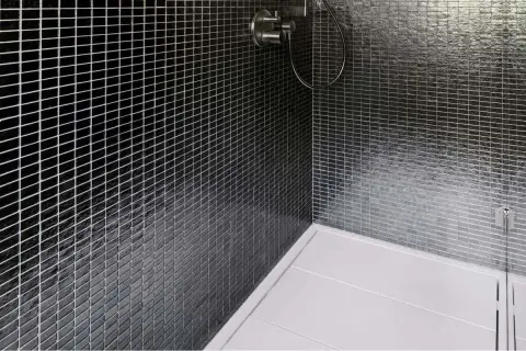 Ducha moderna con azulejos negros brillantes y plato de ducha blanco. La **resina epoxi** en la ducha garantiza un acabado impecable y duradero.