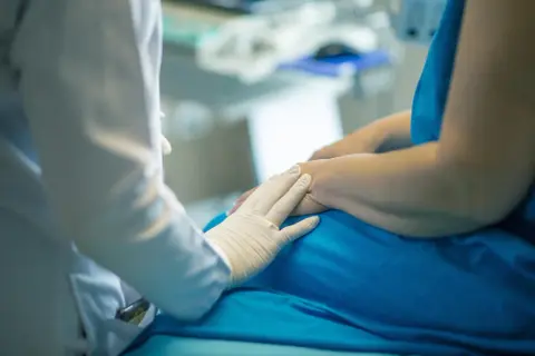Lekarz w białej rękawiczce delikatnie dotyka dłoni pacjenta. Rozmowa o tym, porfiria co to, trwa w tle.