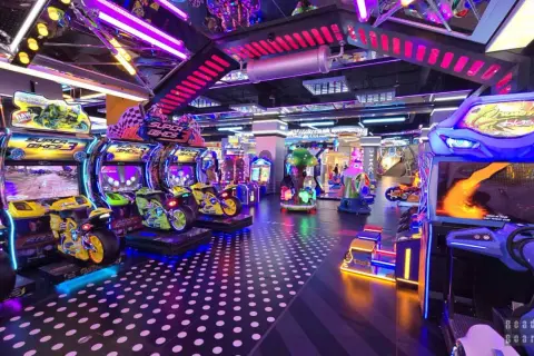 Kolorowy park rozrywki w Łodzi z maszynami do gier, w tym motocyklami i wyścigami.