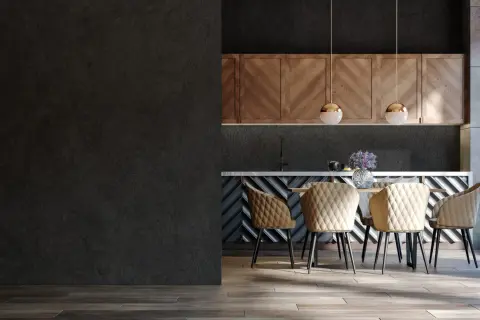 Nowoczesna kuchnia z czarną, betonową ścianą, drewnianymi szafkami i beżowymi krzesłami. Inspiracja, jak zabarwić beton na czarno.