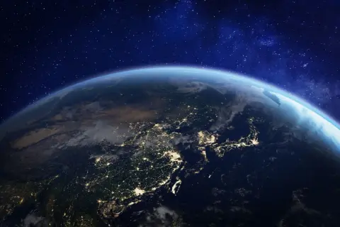 Ziemia nocą z kosmosu, rozświetlona miastami. Widać kontynenty i ocean. To przypomina o tym, jak ważna jest godzina dla Ziemi.