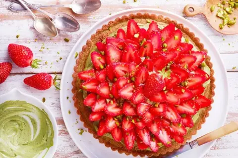 Tarte fraise pistache, une gourmandise aux couleurs vives, garnie de fraises fraîches et de pistaches concassées sur une crème onctueuse.