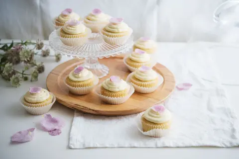 Zarte Cupcakes mit cremiger Glasur und rosa Blütenblättern – süße Ideen für eine Hochzeit.