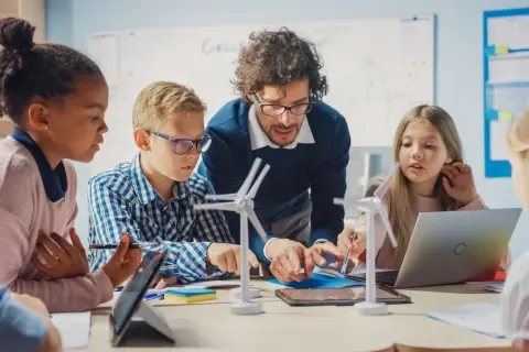 Maestro explica a niños modelos de molinos de viento, un ejemplo de pensamiento computacional aplicado a la energía.