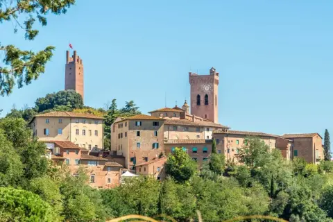Borgo medievale di San Miniato con torri imponenti e case in pietra, immerso nel verde della campagna toscana.
