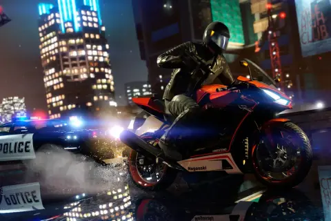 Motocyklista w kasku ucieka przed radiowozem policyjnym w nocnym mieście.