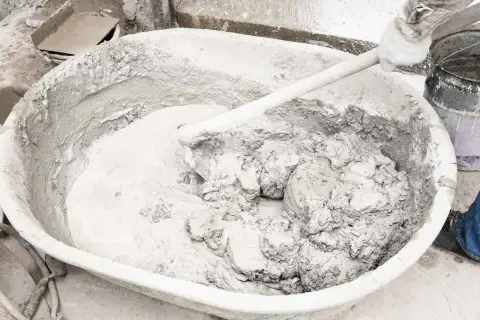 Mieszanie wapna gaszonego z wodą w dużej misie. Powstaje gęsta, szara masa, gotowa do użycia.