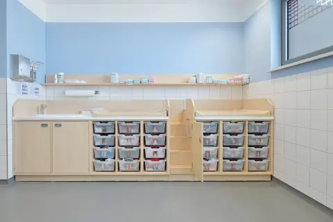 Praktische Elternecke Kita gestalten: Wickeltische, Waschbecken und viele durchsichtige Schubladen für Windeln und Kleidung.