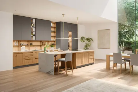 Cuisine moderne avec îlot central en marbre, meubles en bois et gris, et grande fenêtre donnant sur la verdure. Parfaites idées cuisine pour un espace lumineux.