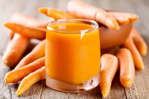 Succo d'arancia brillante circondato da carote fresche, un concentrato di vitamine e benefici per la salute.