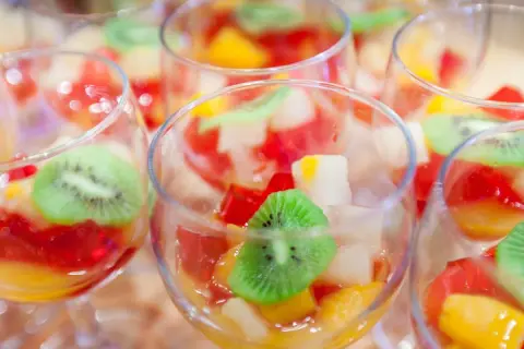 Kolorowe galaretki z owocami, w tym kiwi, w kieliszkach. Czy wiesz, dlaczego galaretka z ananasem nie tężeje?