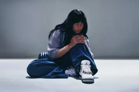 Billie Eilish w luźnych jeansach i stylowych sneakersach, jakby przygotowywała się do koncertu w Polsce.