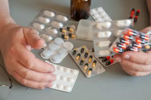 Ręce seniora trzymają opakowania z lekami. Dostępne są darmowe leki dla seniorów, co ułatwia dbanie o zdrowie.