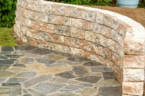 Muretto curvo in pietra per giardino, con pavimentazione irregolare in ardesia. Belle idee per muretti da giardino.