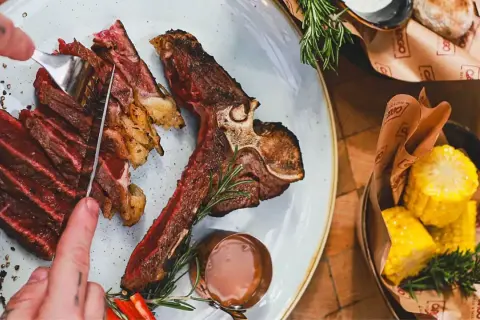 Idealne jakie wino do wołowiny? Soczysty stek T-bone z pieczonymi ziemniakami i kukurydzą.