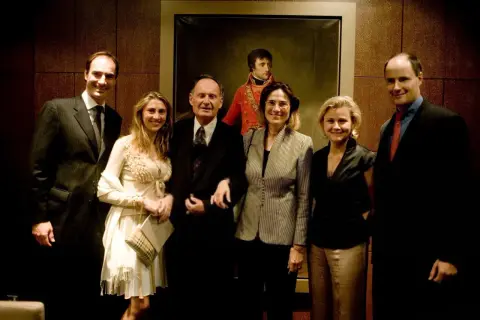 Cinq personnes posent devant un portrait de Napoléon.