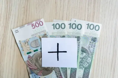 Polskie banknoty 500 i 100 zł. Na białej kartce symbol plusa. Czy to zapowiedź wyższej pensji?