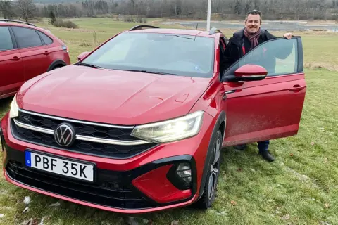 Man med halsduk vid en röd VW Taigo. Bilen är redo för ett vw taigo test i svensk natur.